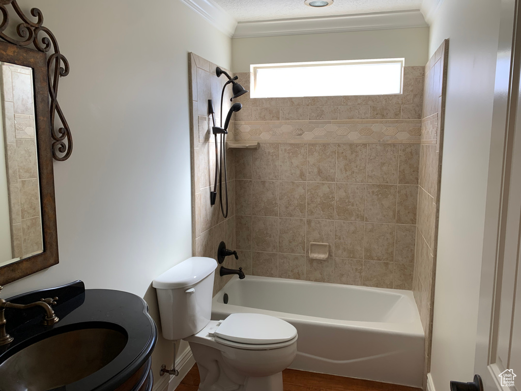 Full bathroom featuring large vanity, tiled shower / bath combo, ornamental molding, and toilet