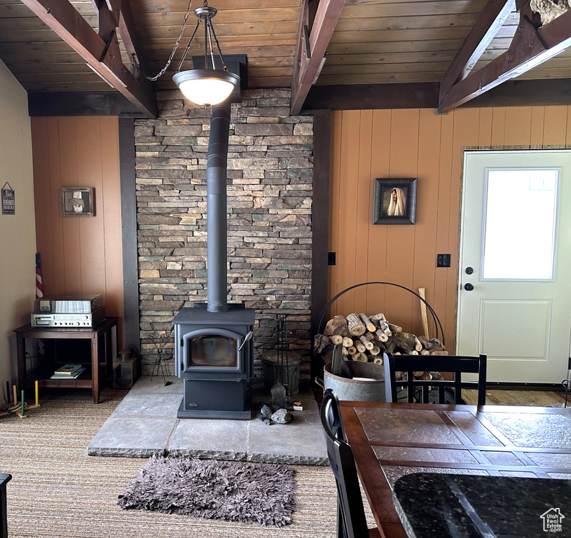 Living room featuring wooden walls, a wood stove, and wooden ceiling