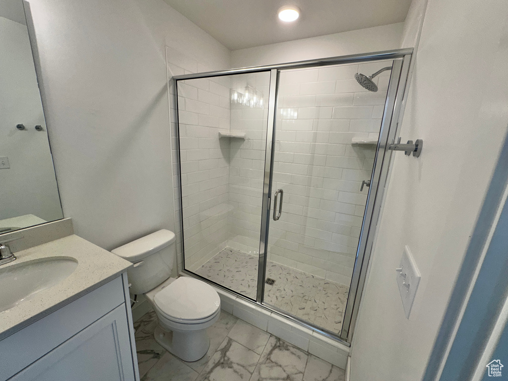 Bathroom with a shower with door, vanity, toilet, and tile flooring