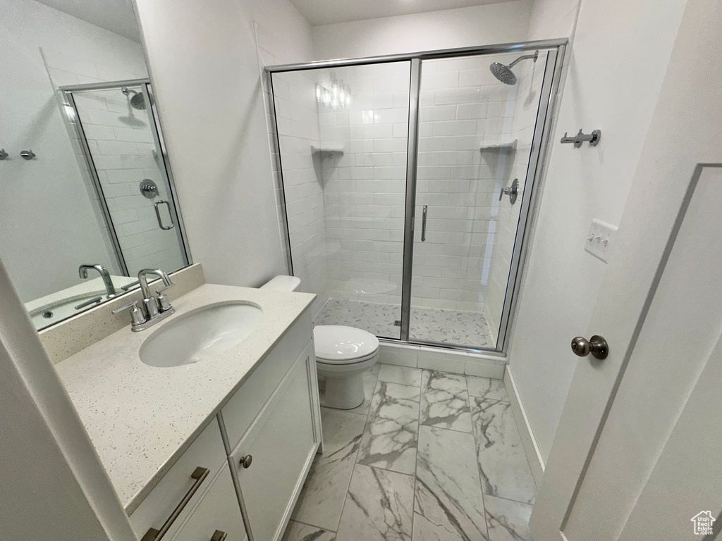 Bathroom with tile flooring, walk in shower, toilet, and large vanity