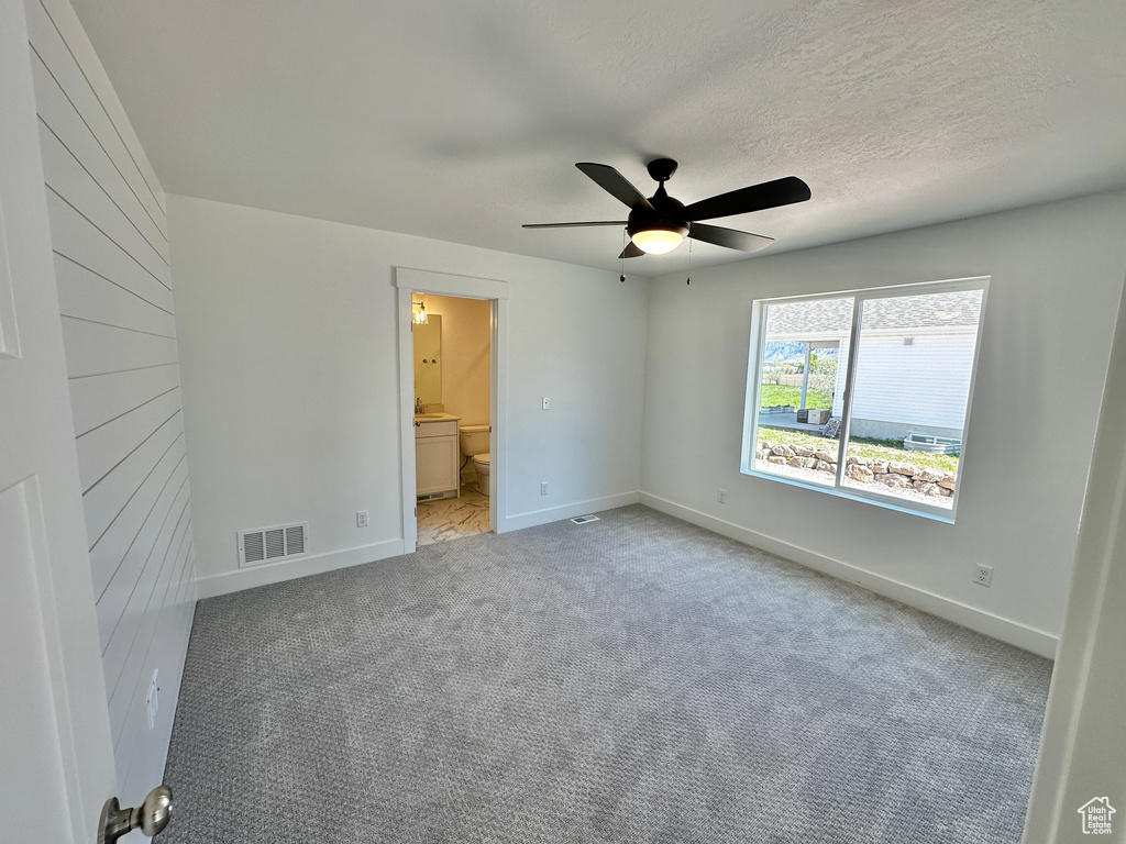 Unfurnished bedroom featuring a textured ceiling, ceiling fan, connected bathroom, and carpet flooring