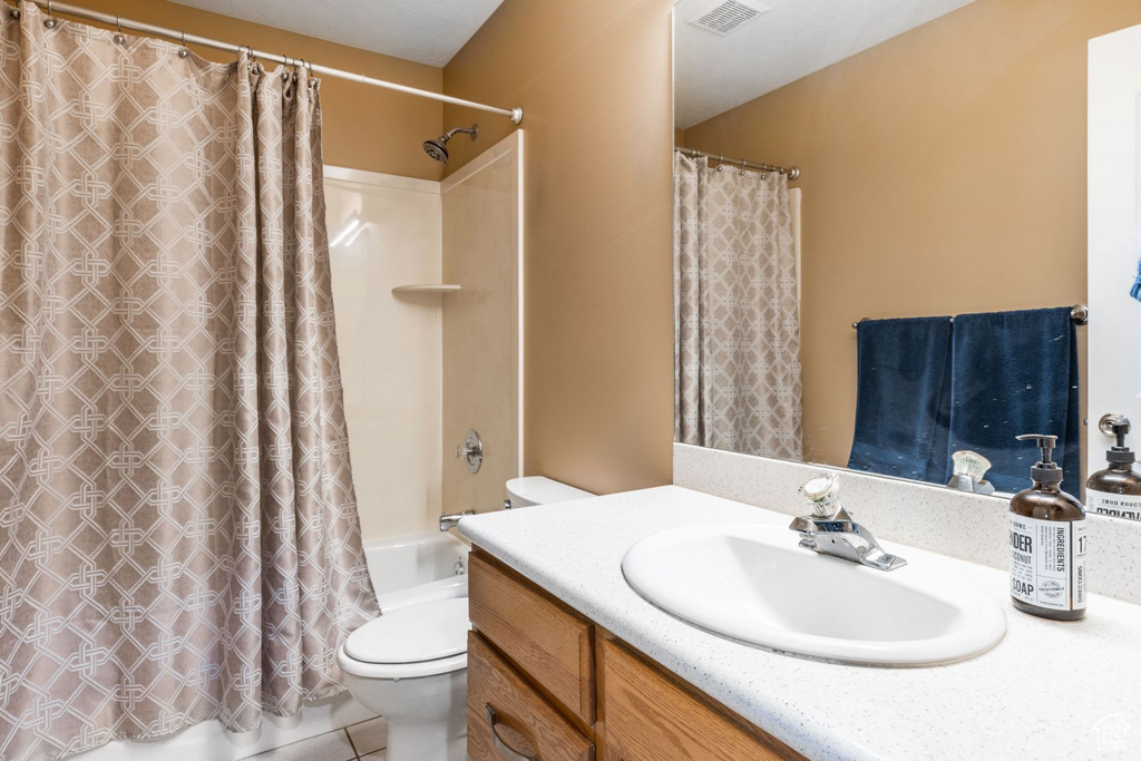 Full bathroom featuring shower / tub combo with curtain, tile floors, vanity, and toilet