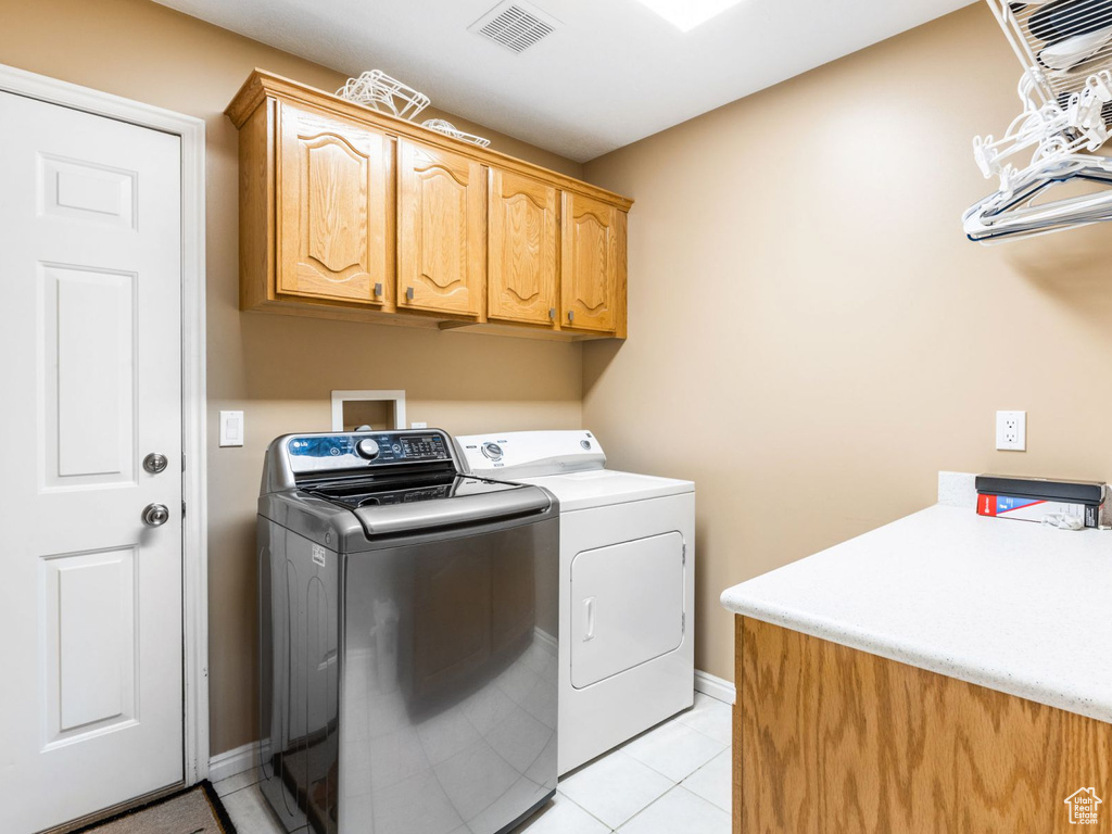 Clothes washing area featuring washer hookup, light tile floors, separate washer and dryer, and cabinets