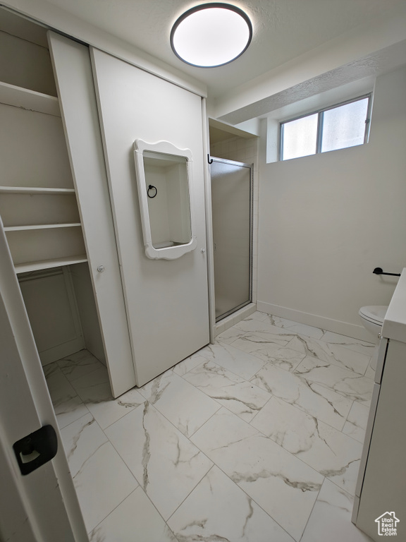 Bathroom featuring a shower with shower door, vanity, tile flooring, and toilet