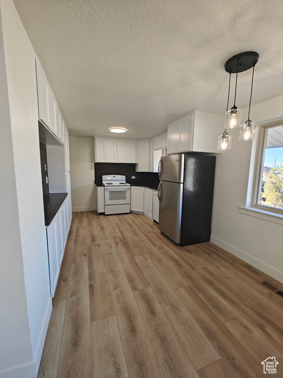 Kitchen featuring light hardwood / wood-style flooring, stainless steel fridge, white electric range, and white cabinets
