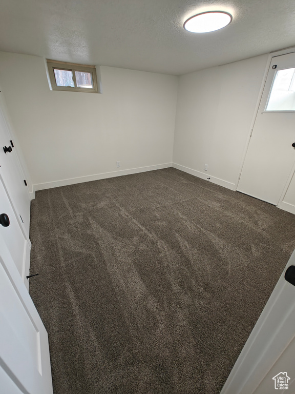 Unfurnished room with dark carpet and a healthy amount of sunlight