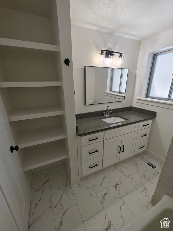 Bathroom featuring tile floors, vanity, and a textured ceiling