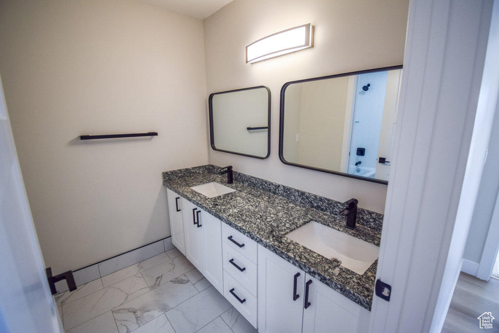 Bathroom with dual sinks, vanity with extensive cabinet space, and tile flooring