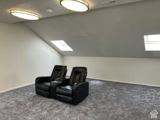 Cinema room featuring dark carpet and lofted ceiling with skylight