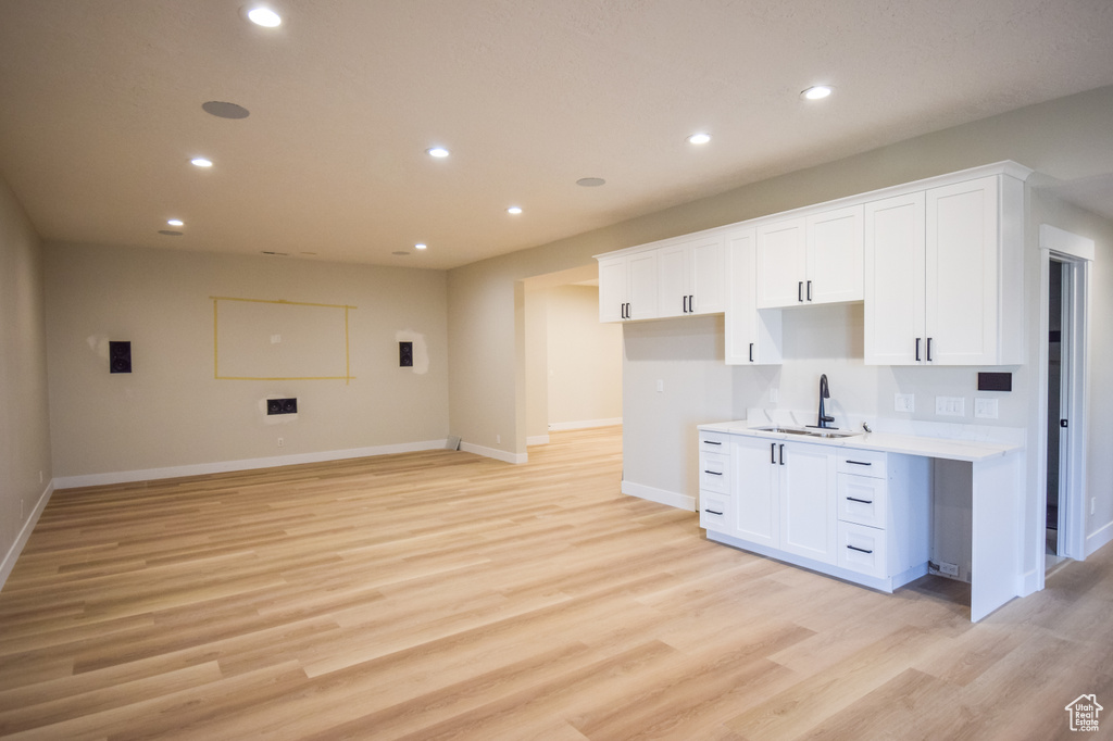 Kitchen with light wood-type flooring, tasteful backsplash, sink, and white cabinetry