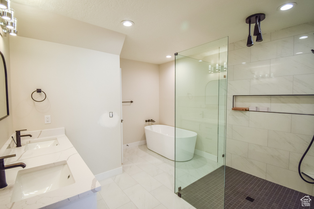 Bathroom featuring dual sinks, large vanity, plus walk in shower, and tile flooring