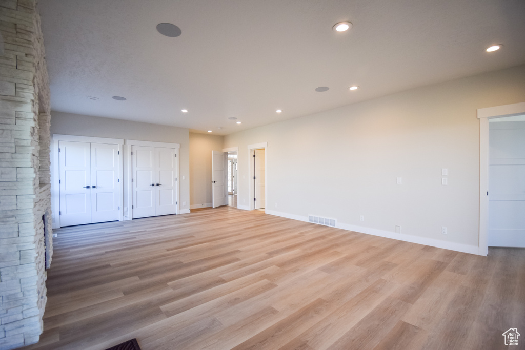 Empty room featuring light hardwood / wood-style floors and a stone fireplace