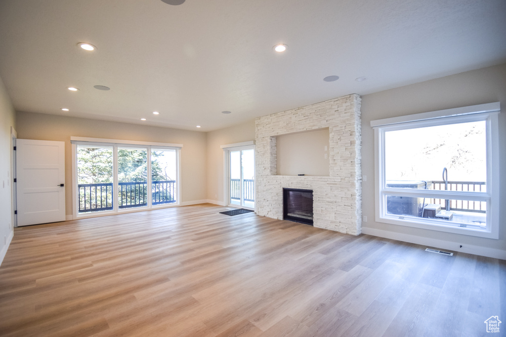 Unfurnished living room featuring a stone fireplace and light hardwood / wood-style flooring