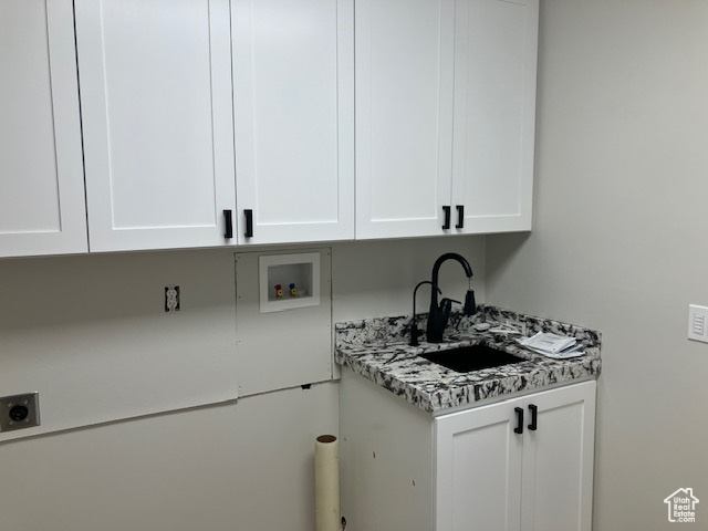 Washroom with sink, hookup for a washing machine, electric dryer hookup, and cabinets