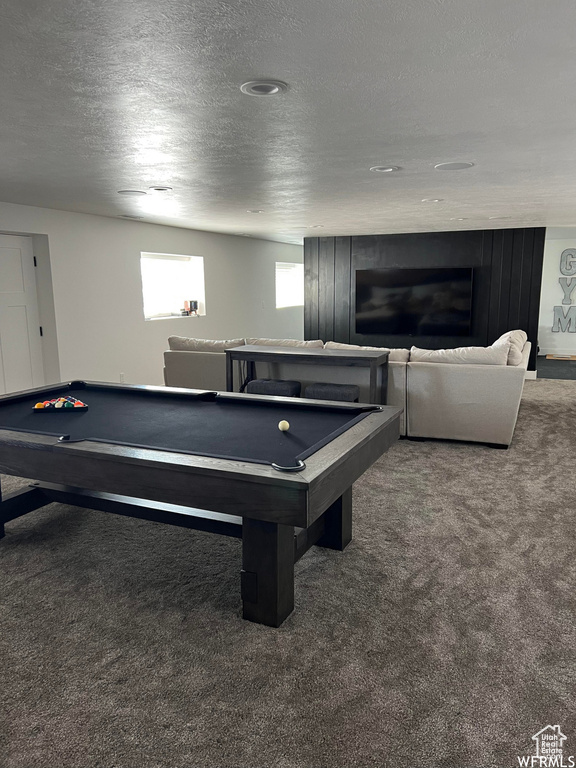 Game room with dark colored carpet, a textured ceiling, and billiards