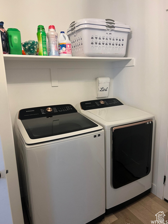 Clothes washing area with dark wood-type flooring and independent washer and dryer