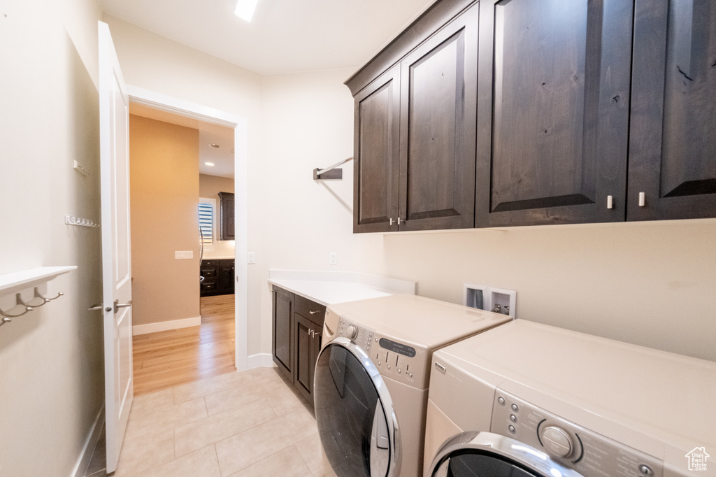 Clothes washing area featuring washer and dryer, light tile flooring, cabinets, and hookup for a washing machine