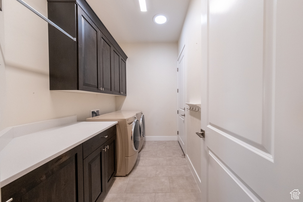 Laundry area with cabinets, light tile flooring, and washing machine and clothes dryer