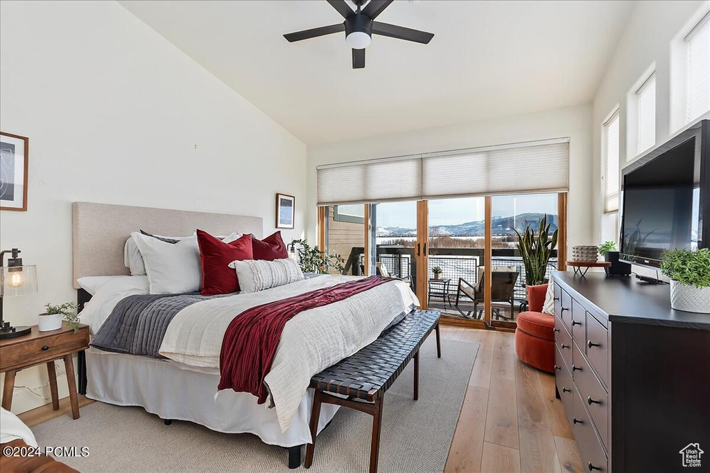 Bedroom with light wood-type flooring, high vaulted ceiling, a mountain view, access to outside, and ceiling fan
