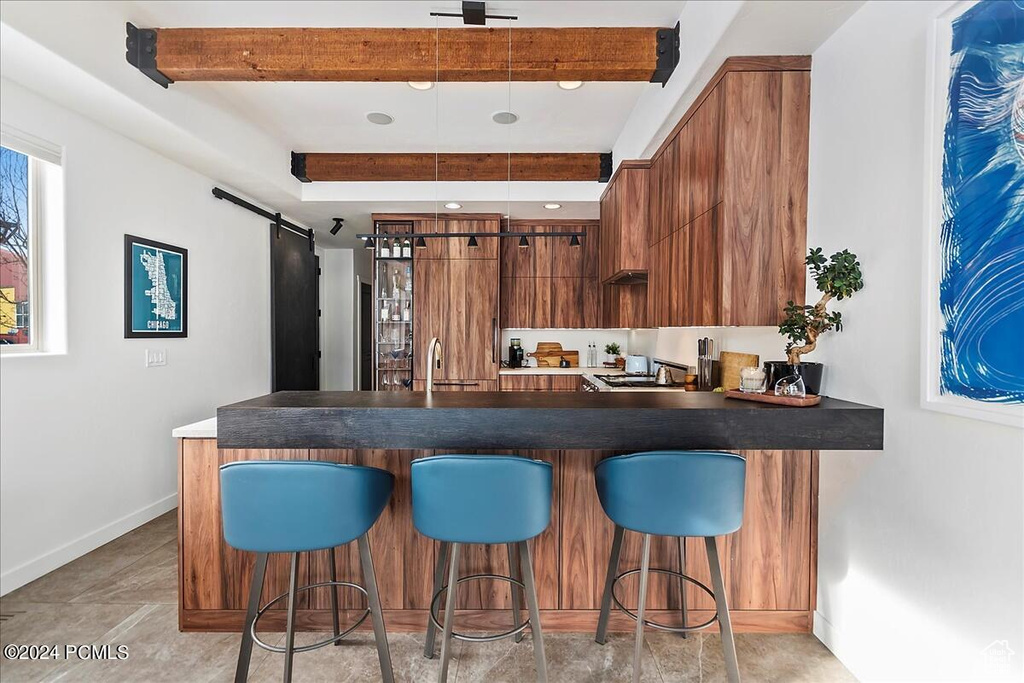 Kitchen with beam ceiling, light tile floors, a kitchen breakfast bar, and kitchen peninsula