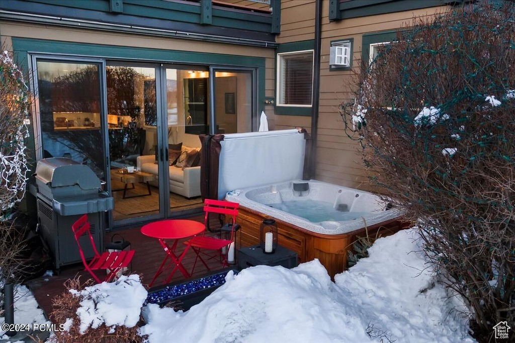 Snow covered patio featuring a grill and a hot tub
