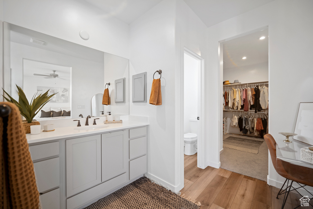 Bathroom with vanity, toilet, ceiling fan, and wood-type flooring