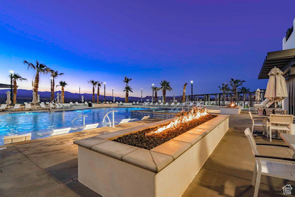 Pool at dusk featuring a patio area and a fire pit