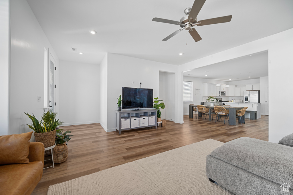 Living room with light hardwood / wood-style floors and ceiling fan