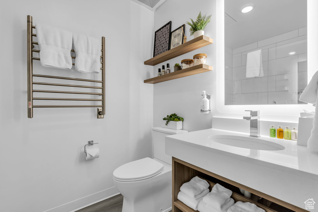 Bathroom featuring vanity, toilet, hardwood / wood-style floors, and radiator heating unit