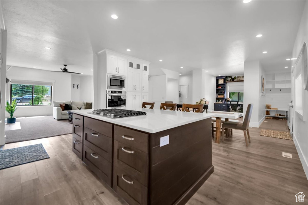Kitchen featuring stainless steel appliances, white cabinetry, dark brown cabinetry, light hardwood / wood-style floors, and ceiling fan