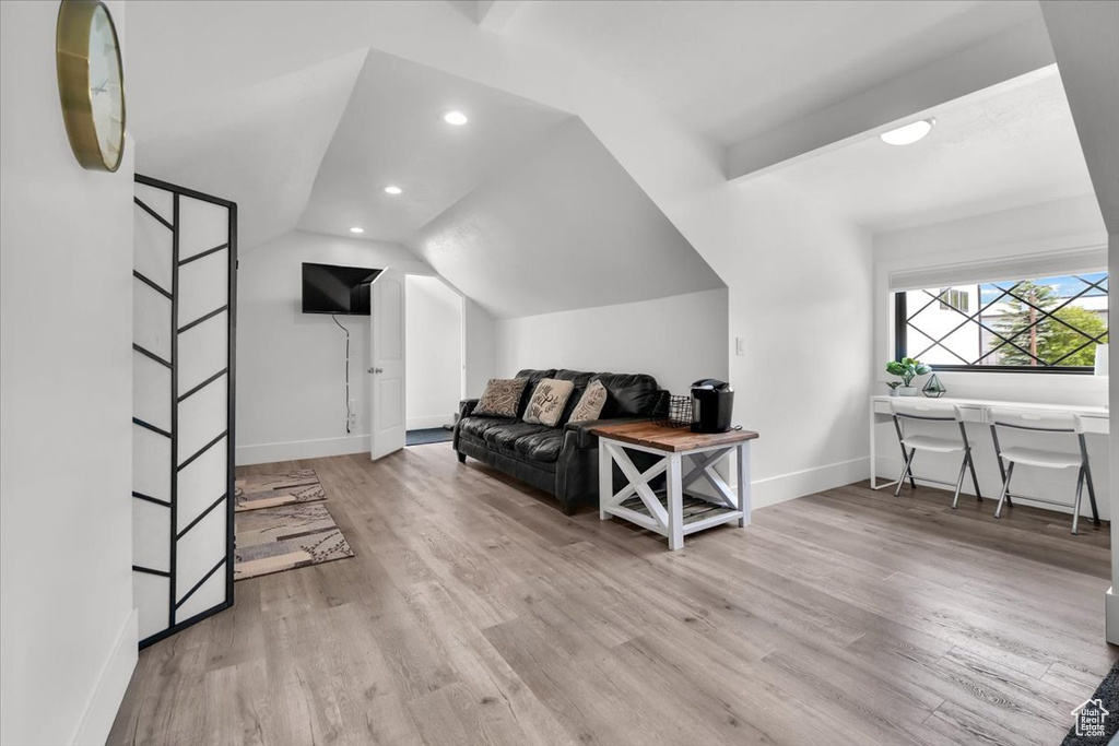 Additional living space with light hardwood / wood-style floors and lofted ceiling
