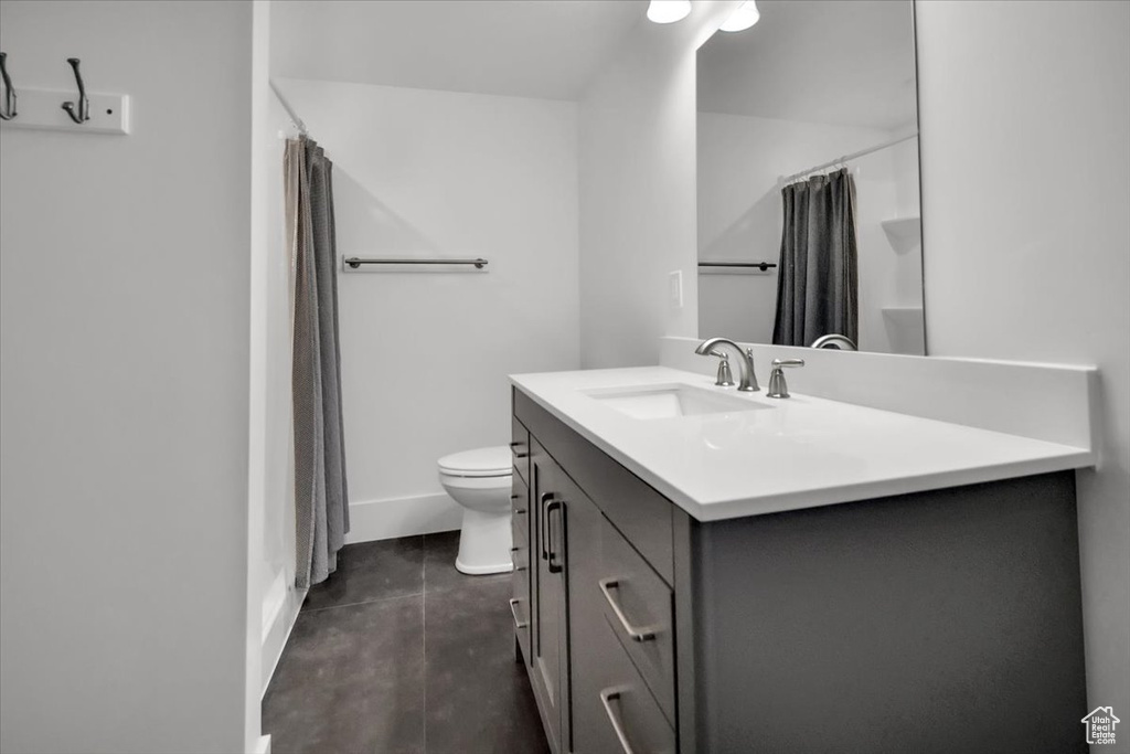 Full bathroom with shower / bathtub combination with curtain, vanity, tile flooring, and toilet