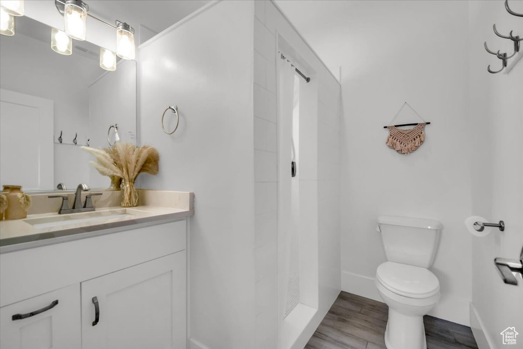 Bathroom featuring vanity, toilet, hardwood / wood-style flooring, and a shower