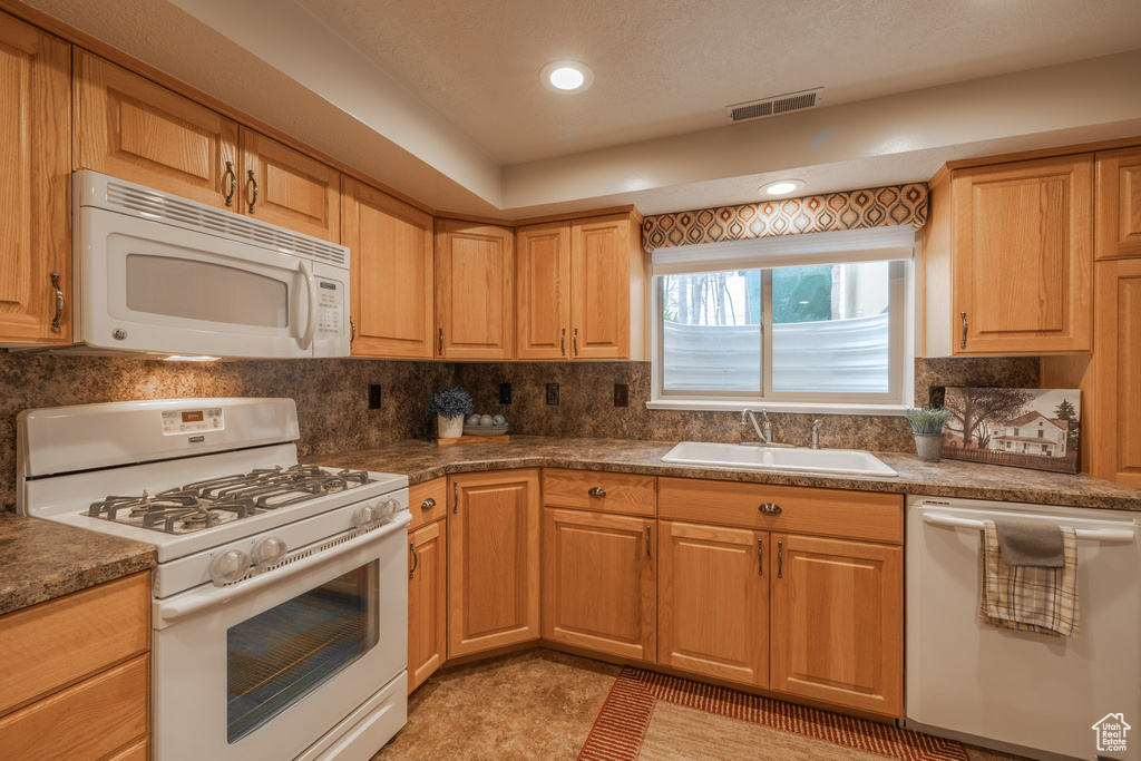 Kitchen featuring white appliances, light tile floors, backsplash, and sink
