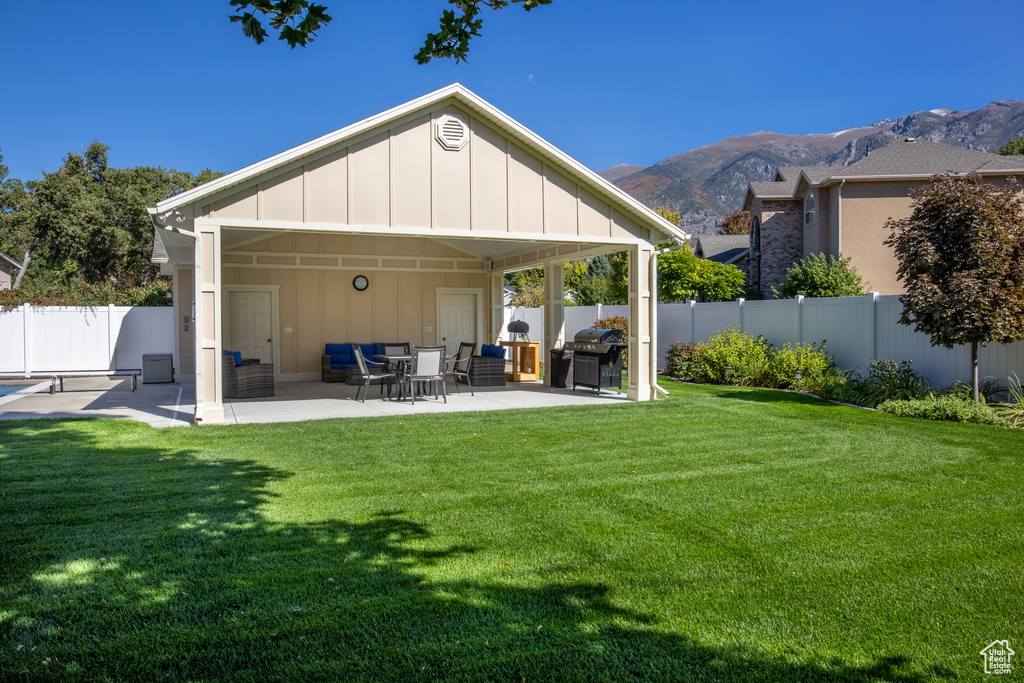 Back of property featuring a mountain view, a lawn, and a patio