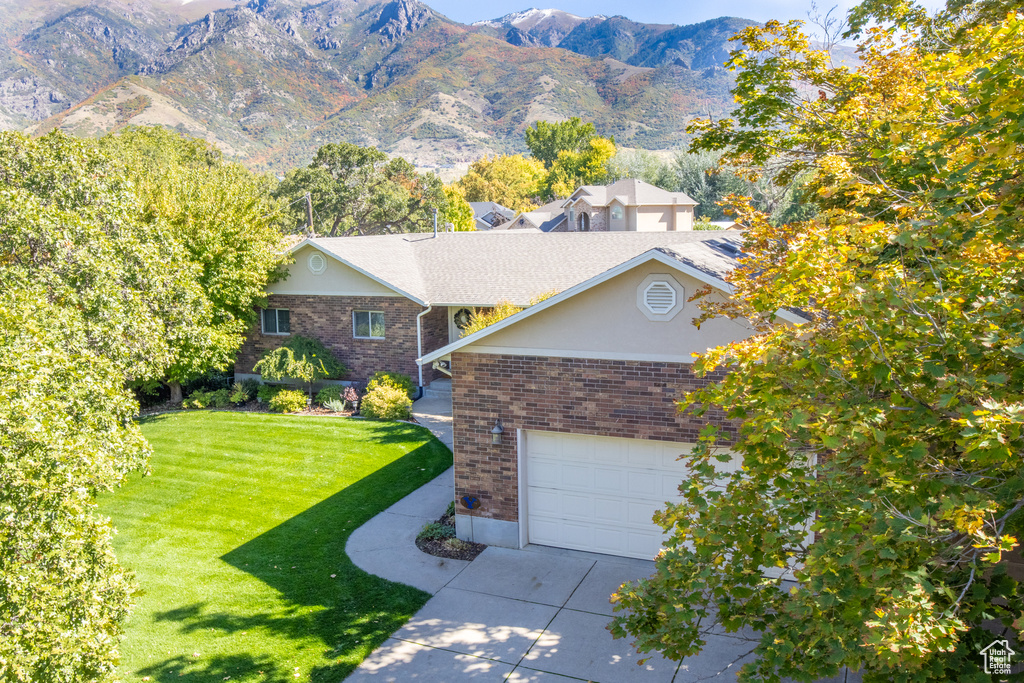 View of front of house with a front yard, a garage, and a mountain view