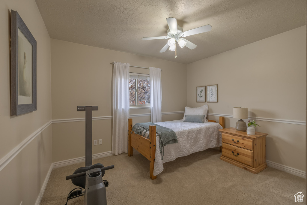Bedroom with ceiling fan, a textured ceiling, and light carpet