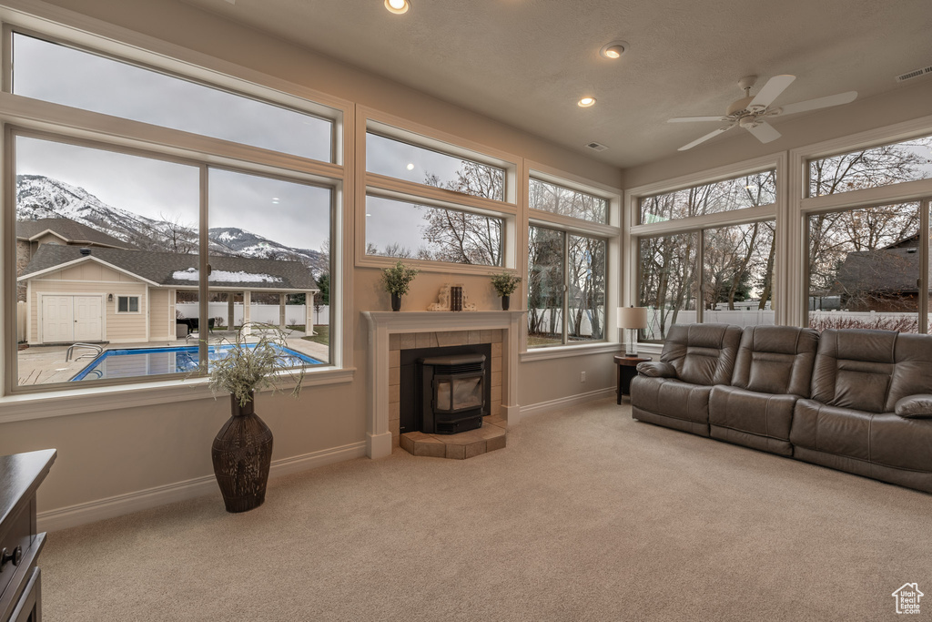 Sunroom with a mountain view, a wealth of natural light, a fireplace, and ceiling fan