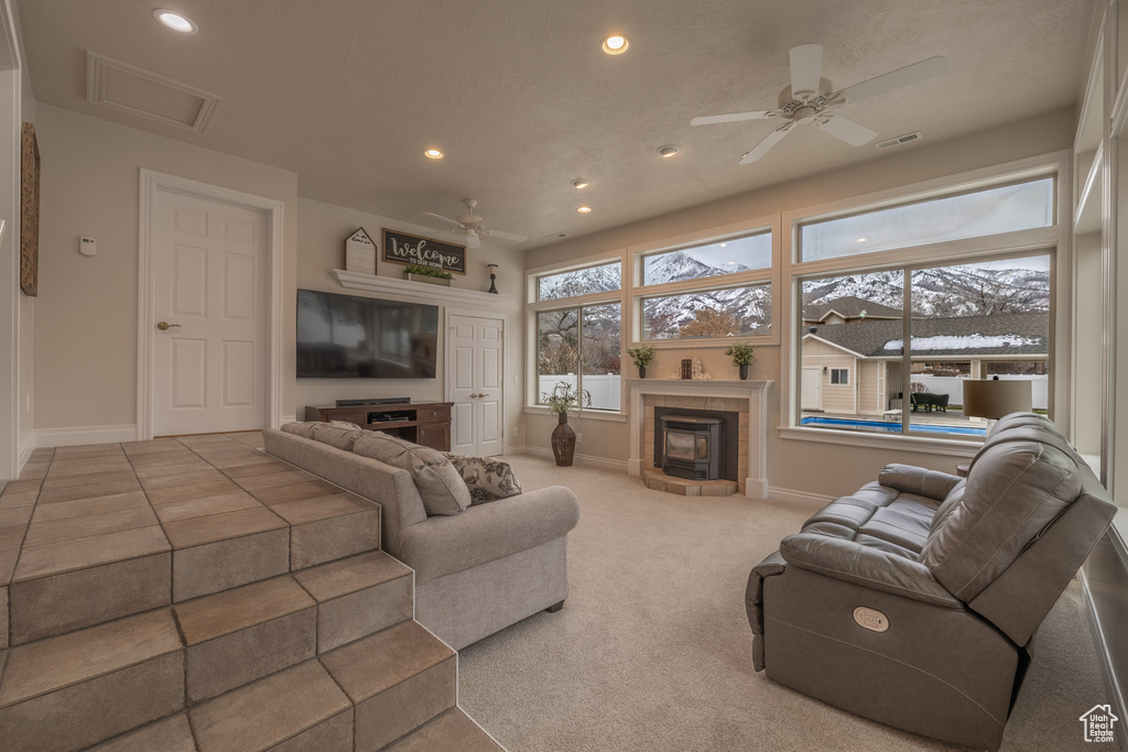 Carpeted living room featuring a fireplace and ceiling fan