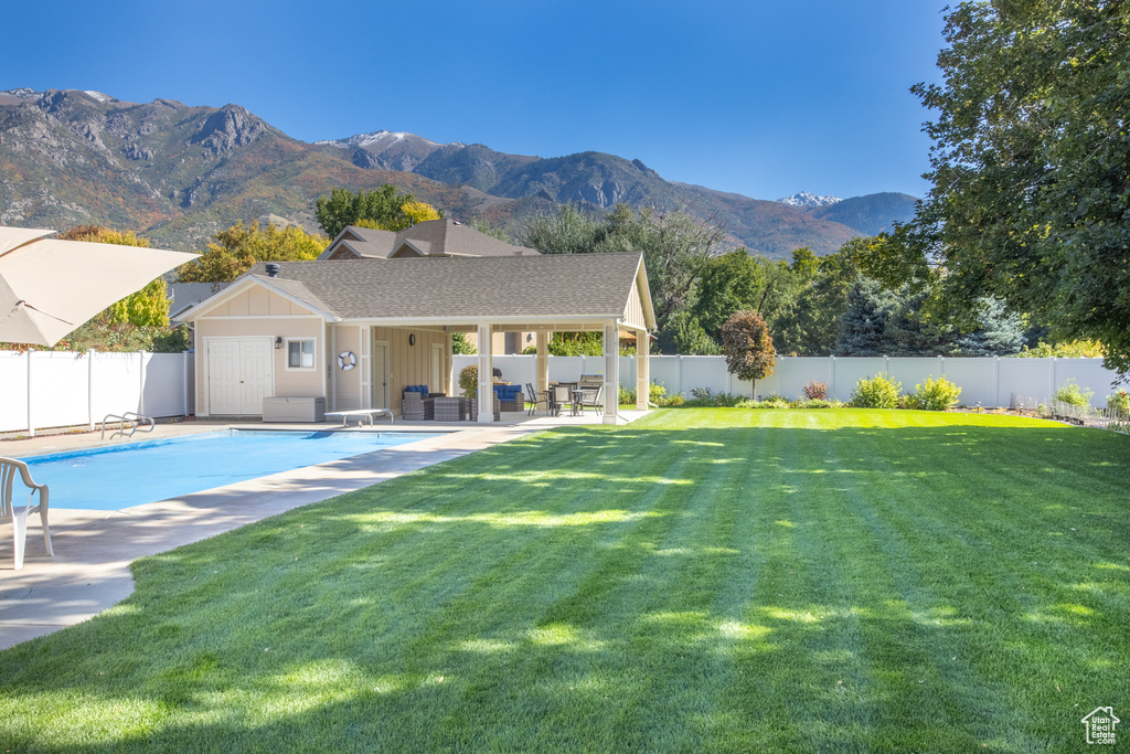 Back of property with a mountain view, a lawn, a patio, and a fenced in pool
