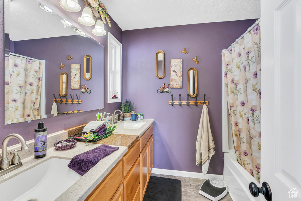 Bathroom featuring wood-type flooring, double sink vanity, and shower / bath combo