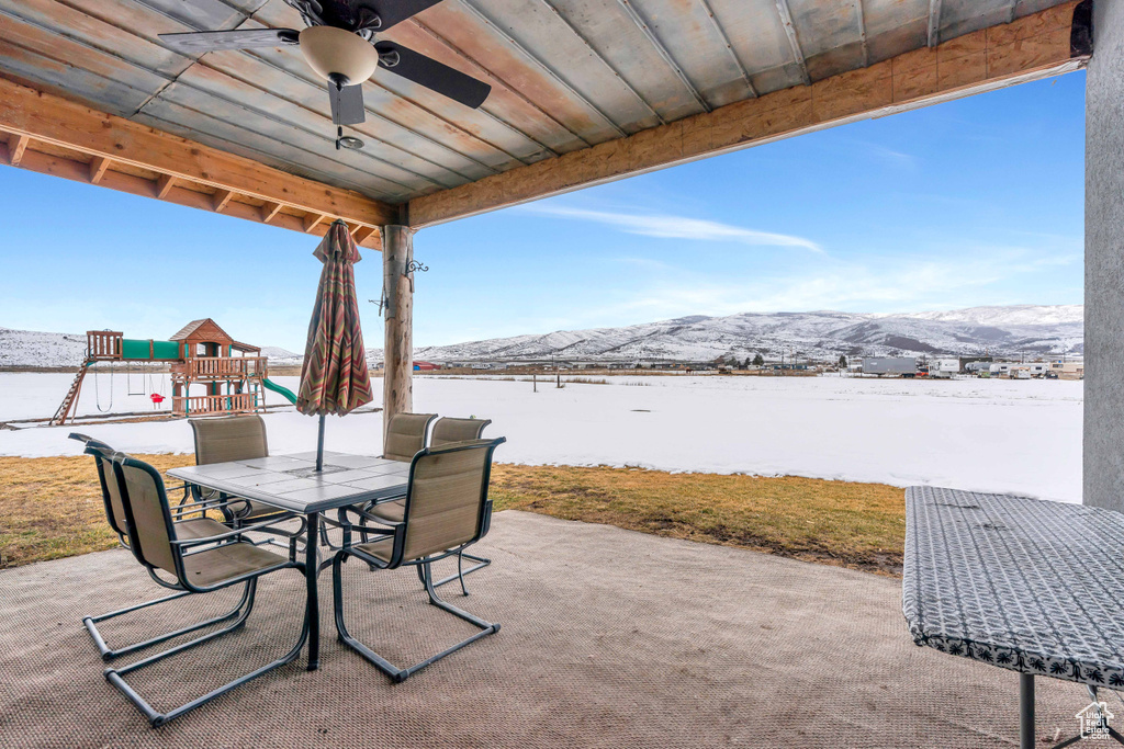 Snow covered patio featuring a mountain view and ceiling fan