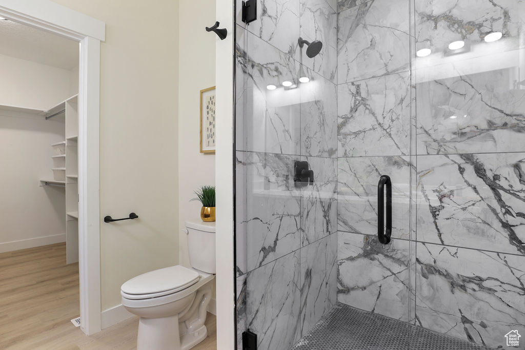 Bathroom with wood-type flooring, an enclosed shower, and toilet