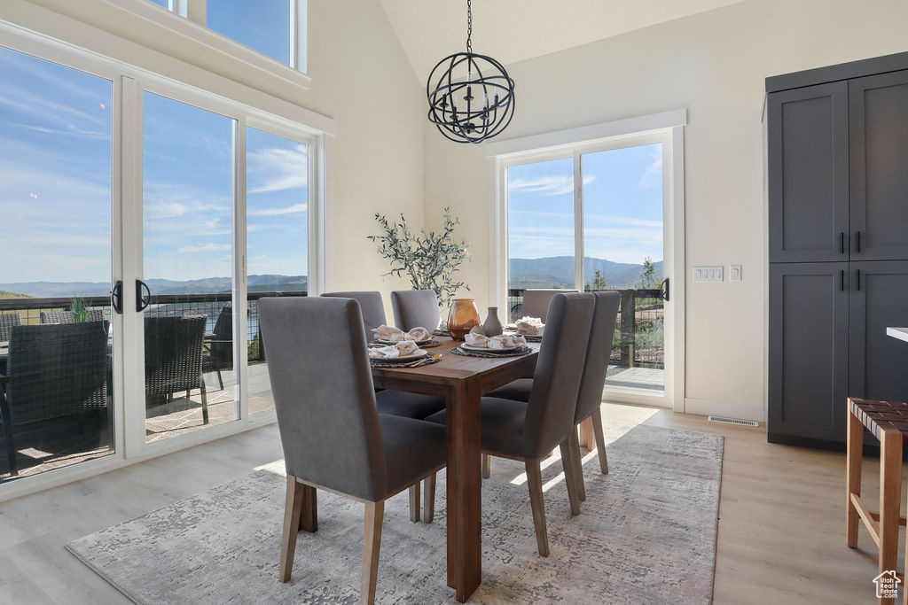 Dining room with plenty of natural light, a notable chandelier, and light wood-type flooring