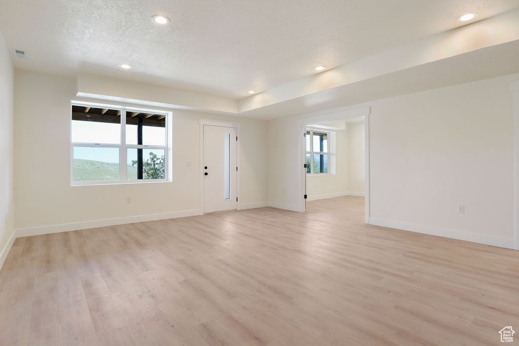 Unfurnished room with light hardwood / wood-style flooring, a textured ceiling, and a wealth of natural light