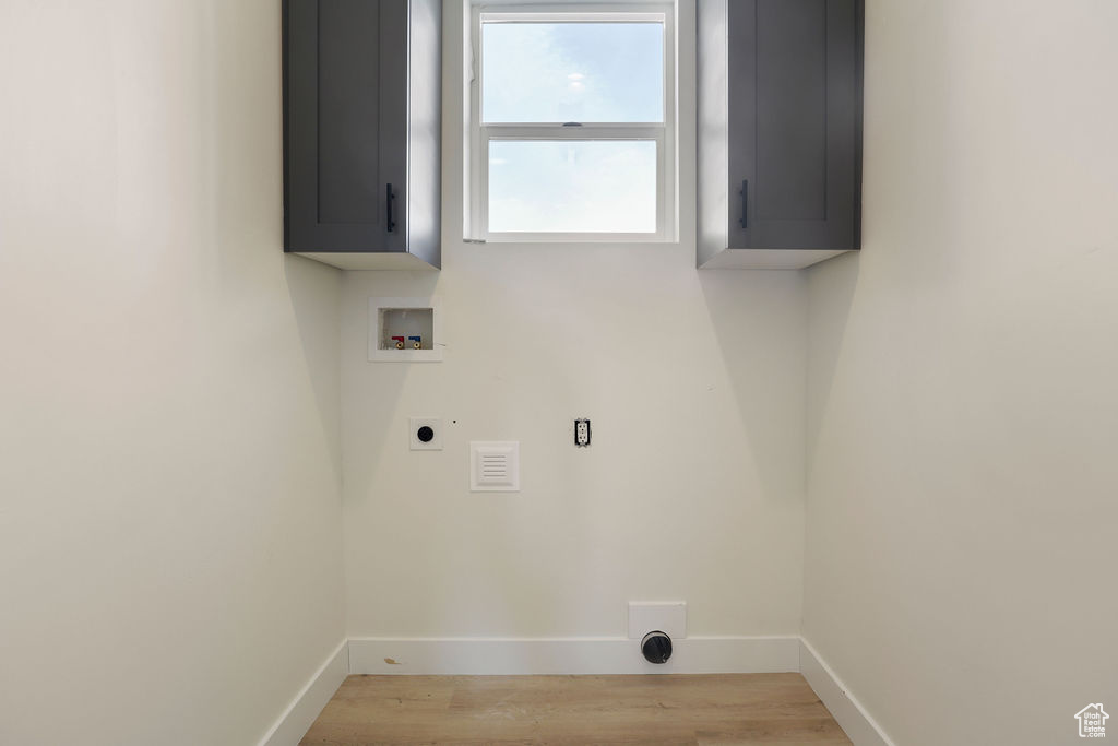 Laundry room featuring light hardwood / wood-style floors, cabinets, electric dryer hookup, and washer hookup