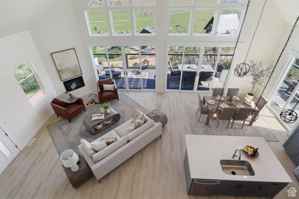 Living room with a wealth of natural light, a high ceiling, and light wood-type flooring