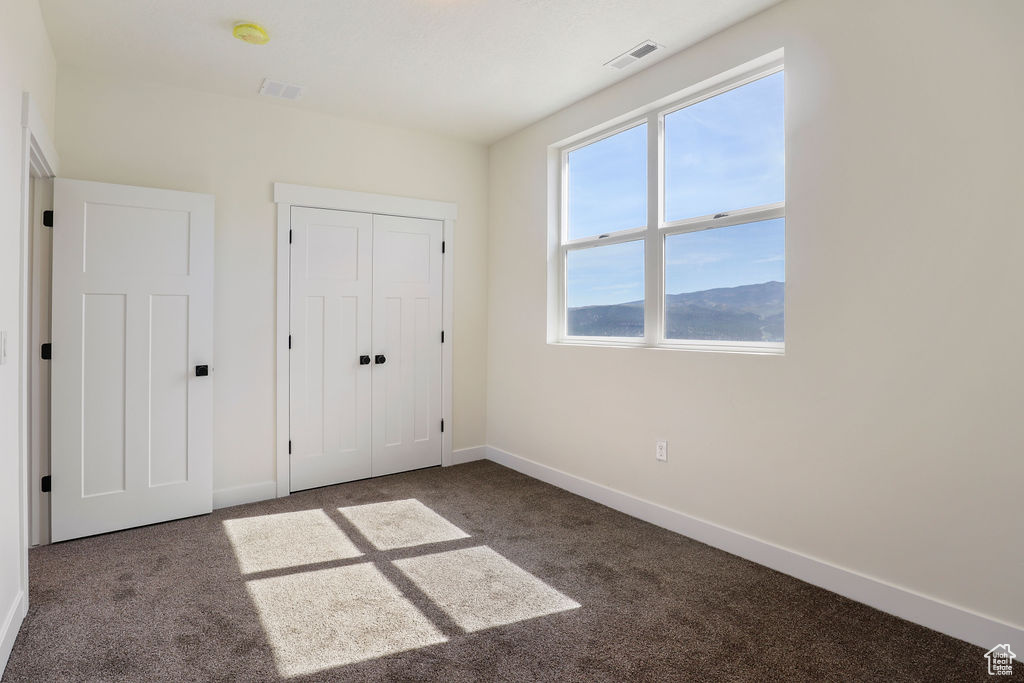 Unfurnished bedroom featuring dark carpet and a closet