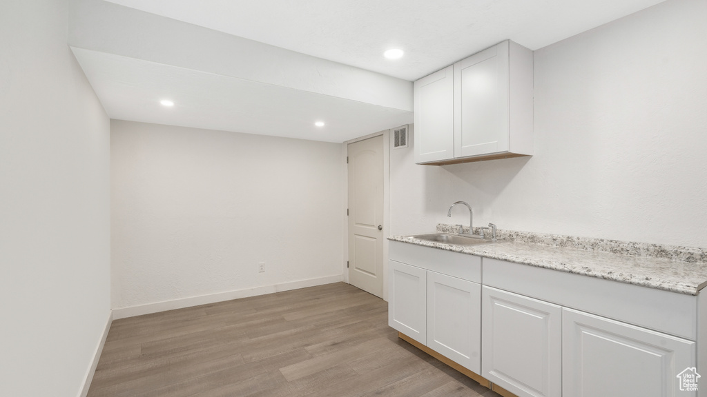 Interior space with white cabinets, light hardwood / wood-style flooring, and sink