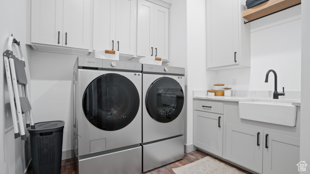 Clothes washing area featuring cabinets, dark hardwood / wood-style flooring, sink, and washer and clothes dryer